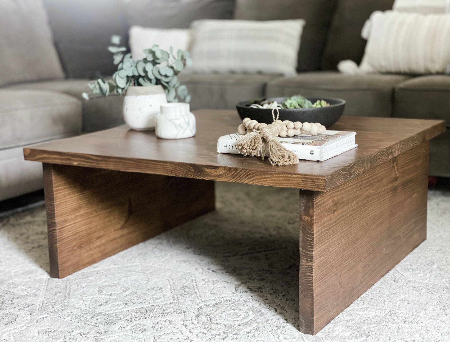 Modern living room with handcrafted square coffee table in foreground.